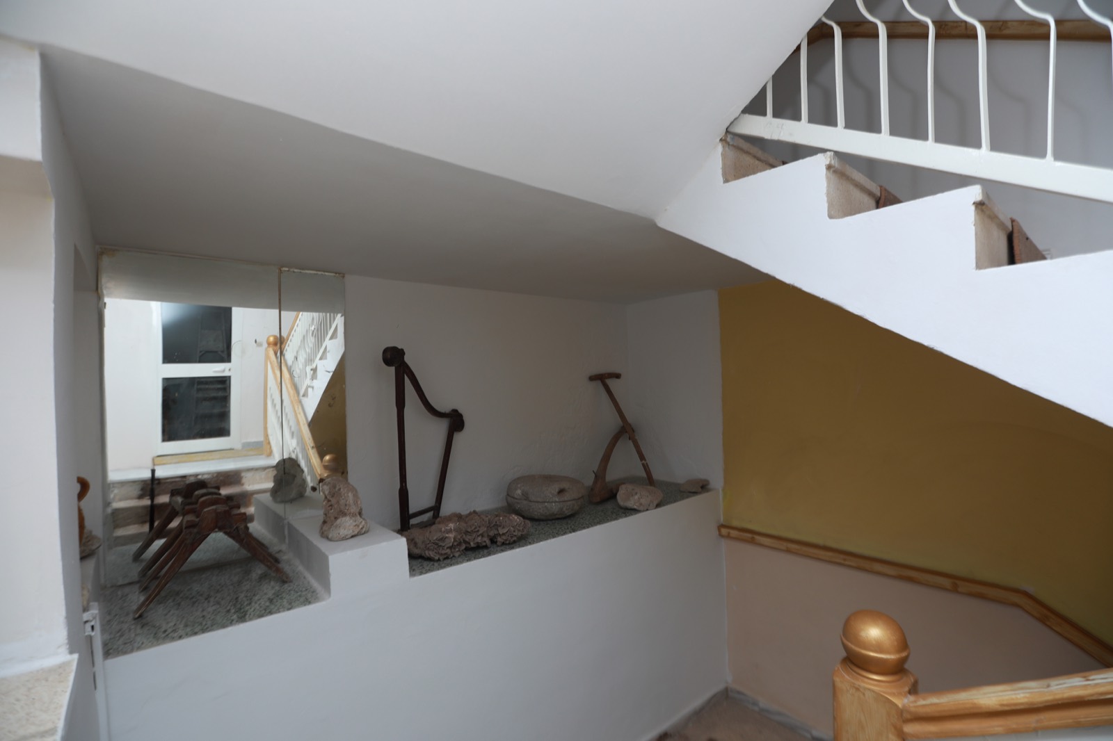 Escalier de l'hôtel décoré d'outils anciens et de pierres taillées